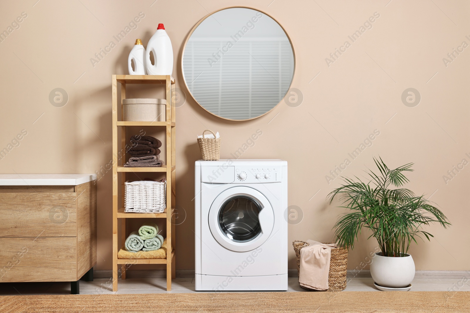 Photo of Stylish laundry room interior with washing machine, furniture and houseplant