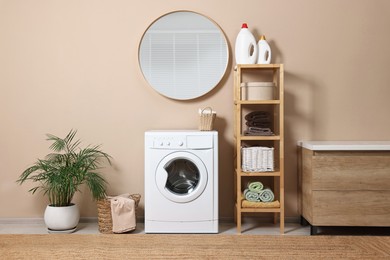 Photo of Stylish laundry room interior with washing machine, furniture and houseplant