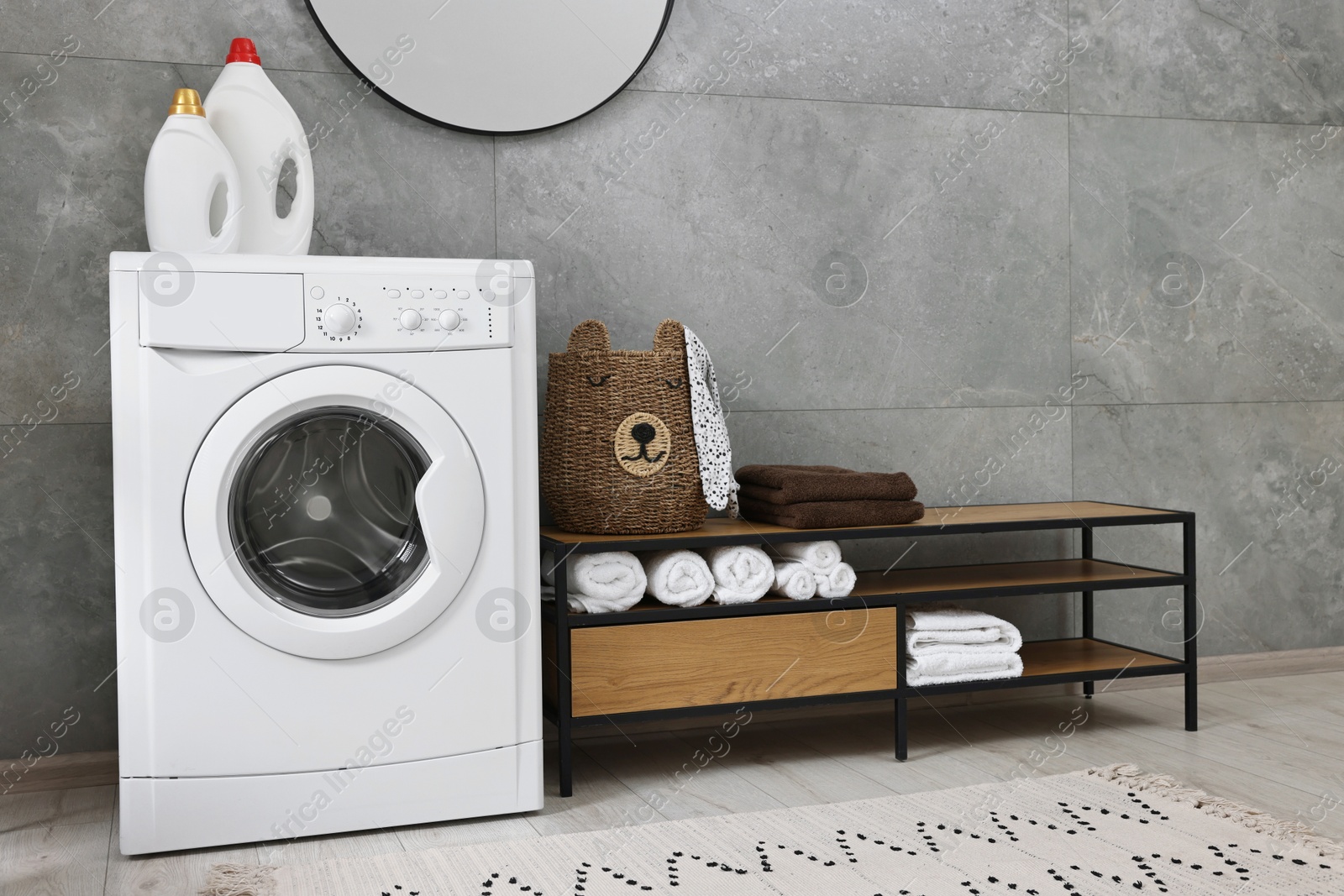 Photo of Washing machine, detergents, towels, basket and storage cabinet in laundry room