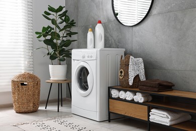 Washing machine, detergents, houseplant, baskets and storage cabinet in laundry room