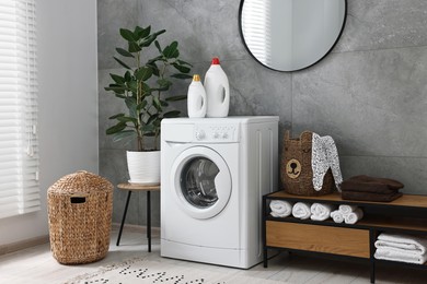 Washing machine, detergents, houseplant, baskets and storage cabinet in laundry room