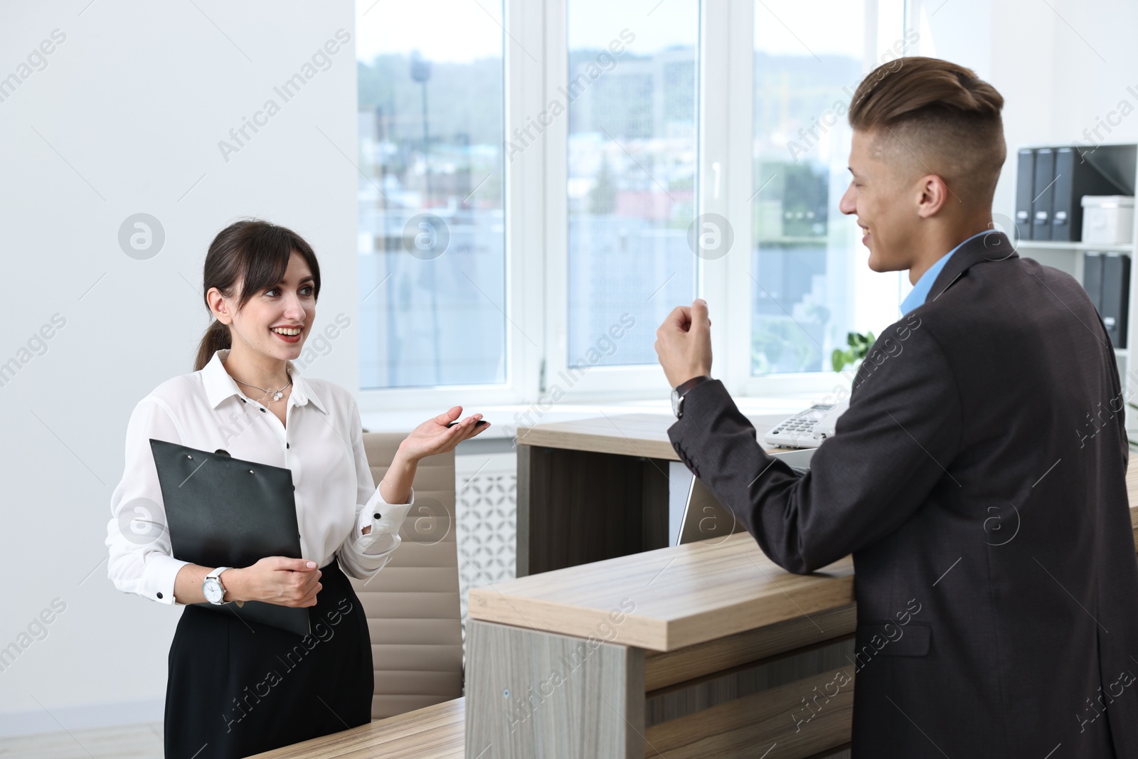 Photo of Professional receptionist working with client in office