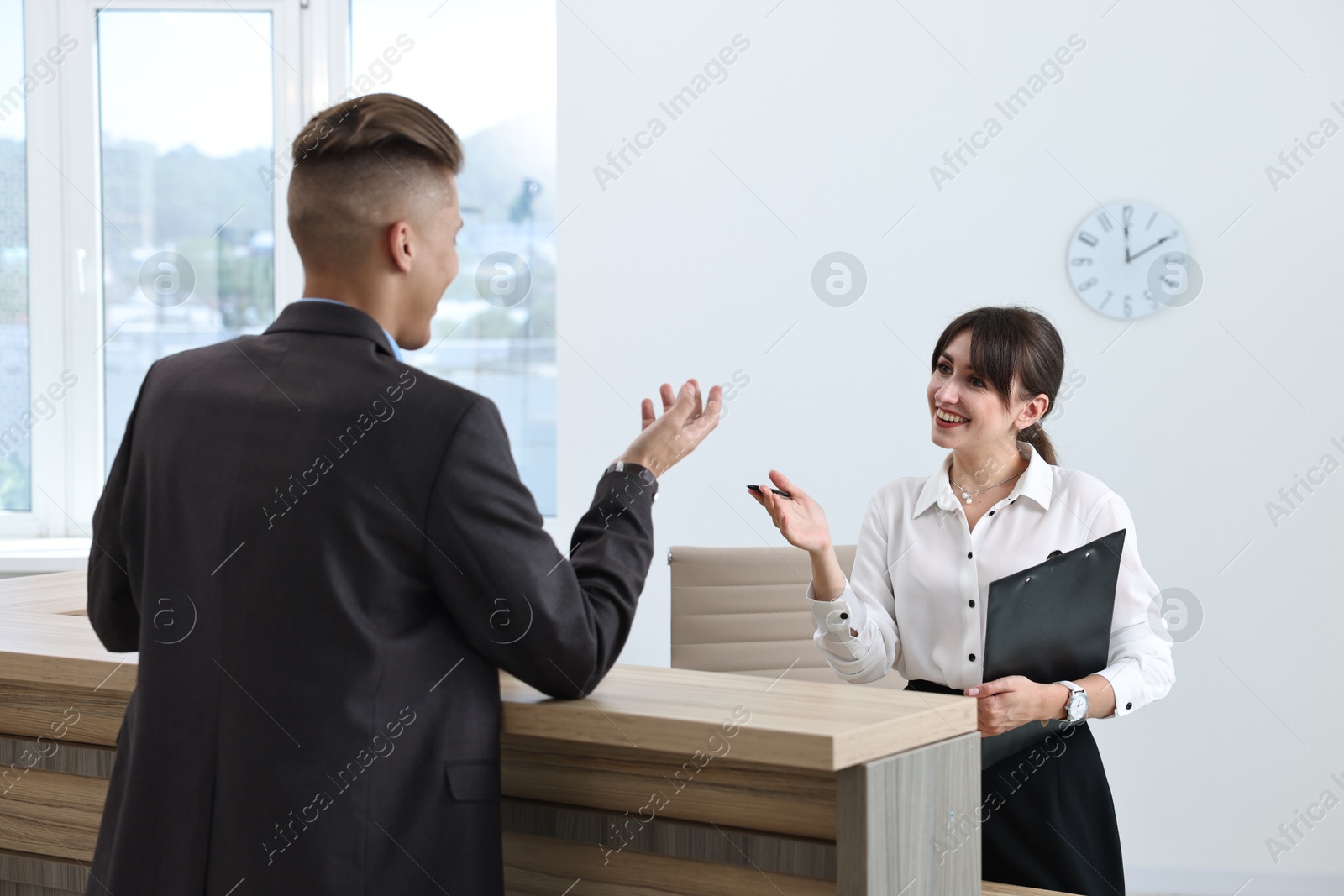 Photo of Professional receptionist working with client in office