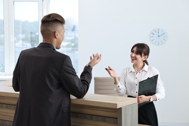 Photo of Professional receptionist working with client in office