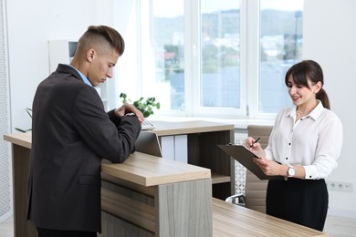Photo of Professional receptionist working with client in office