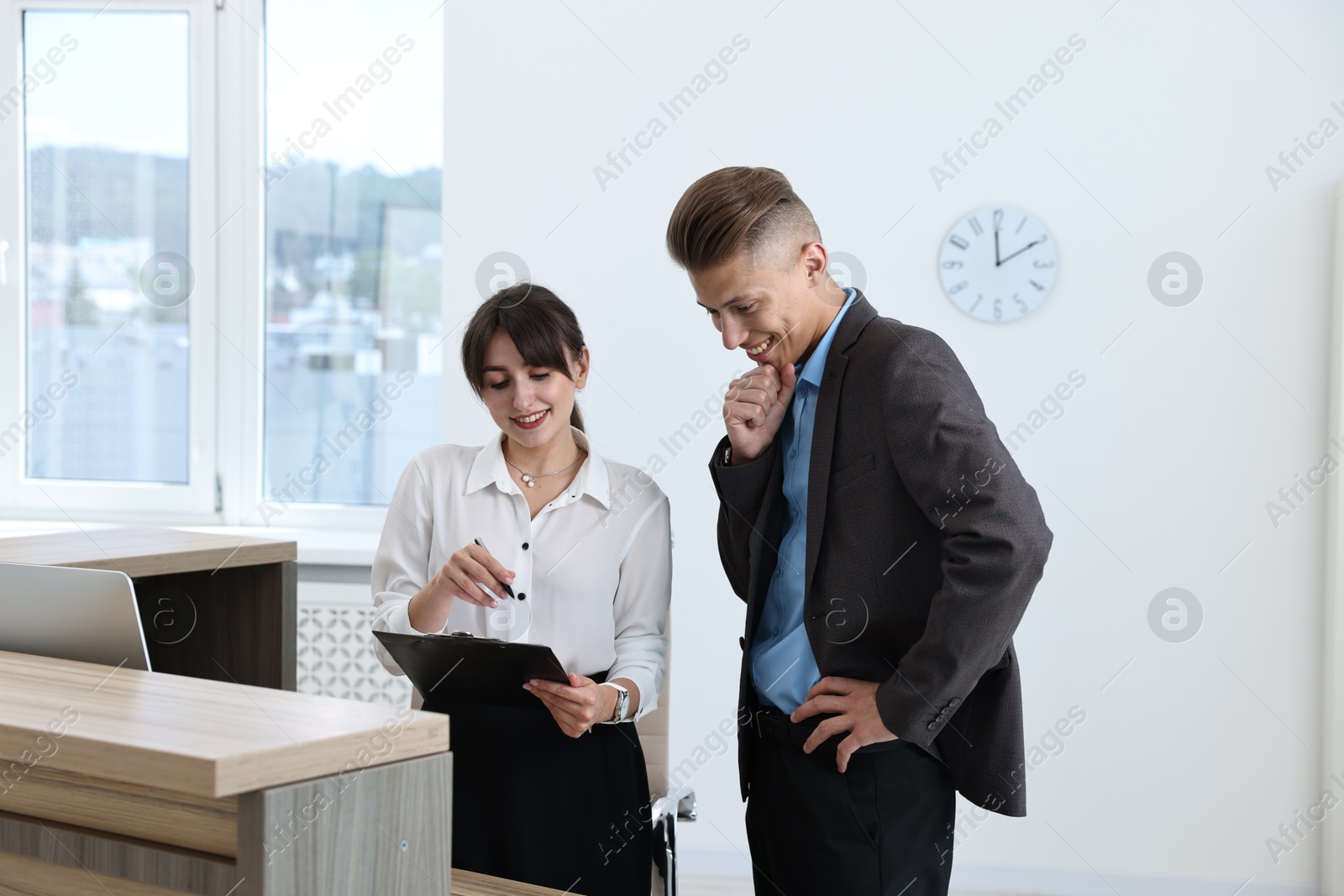 Photo of Professional receptionist working with client in office