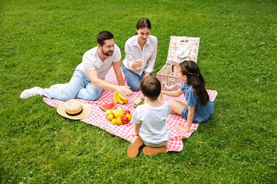 Photo of Family playing rock, paper and scissors during picnic outdoors