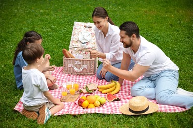 Photo of Happy family playing rock, paper and scissors during picnic in park