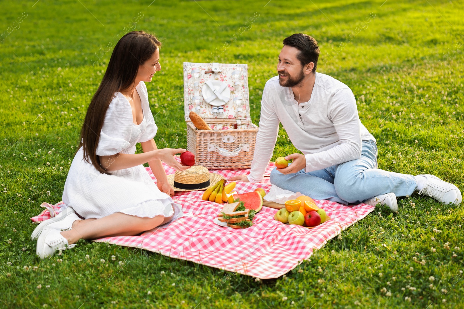 Photo of Happy couple having picnic on green grass outdoors