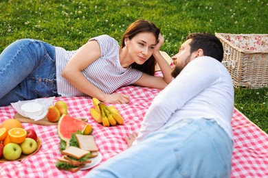 Photo of Lovely couple having picnic on green grass outdoors