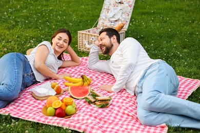 Photo of Happy couple having picnic on green grass outdoors
