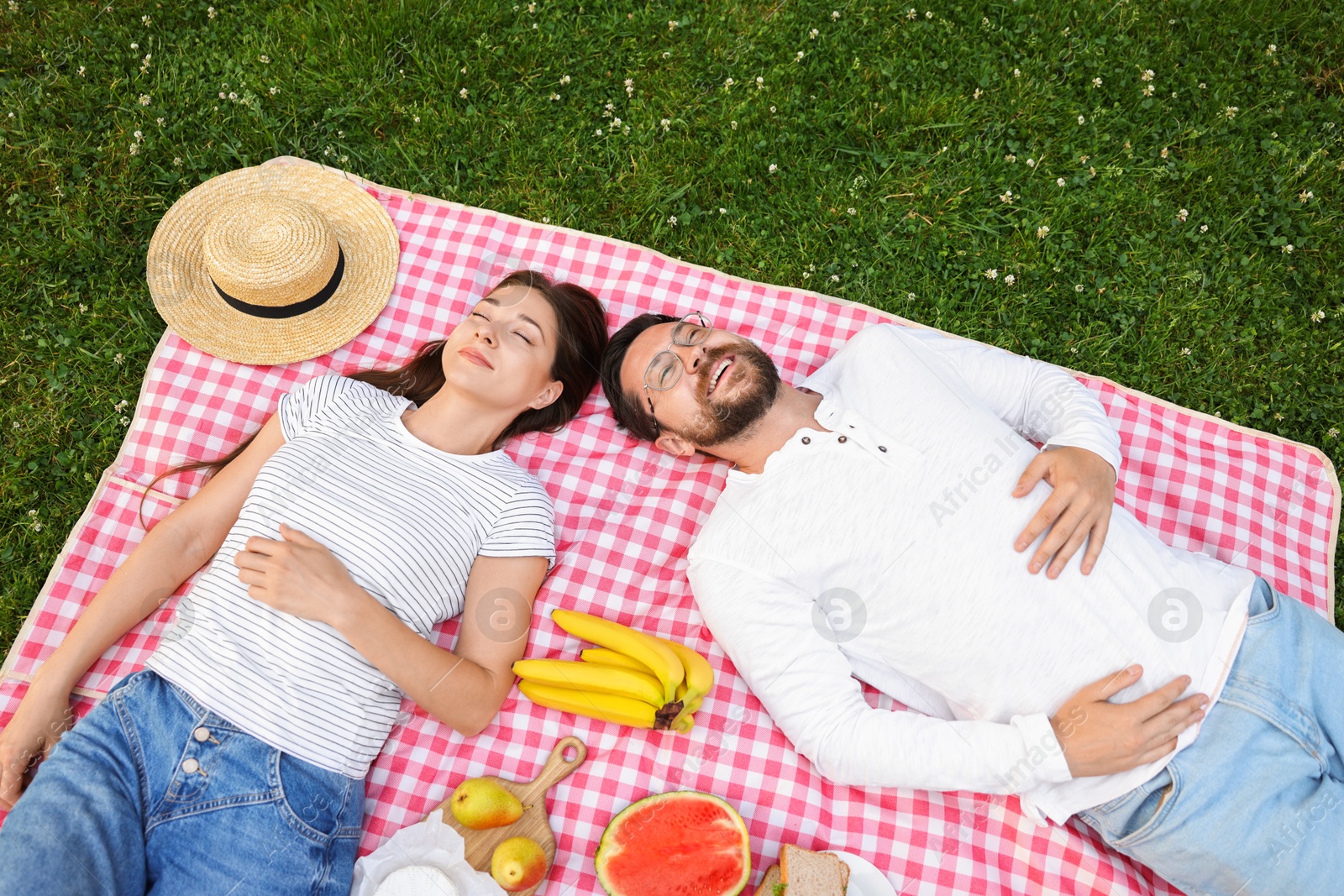 Photo of Romantic picnic. Happy couple relaxing together on green grass outdoors, top view