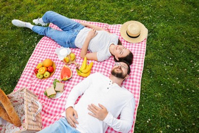 Photo of Romantic picnic. Happy couple relaxing together on green grass outdoors, above view