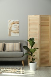 Photo of Wooden folding screen, sofa and houseplant in living room