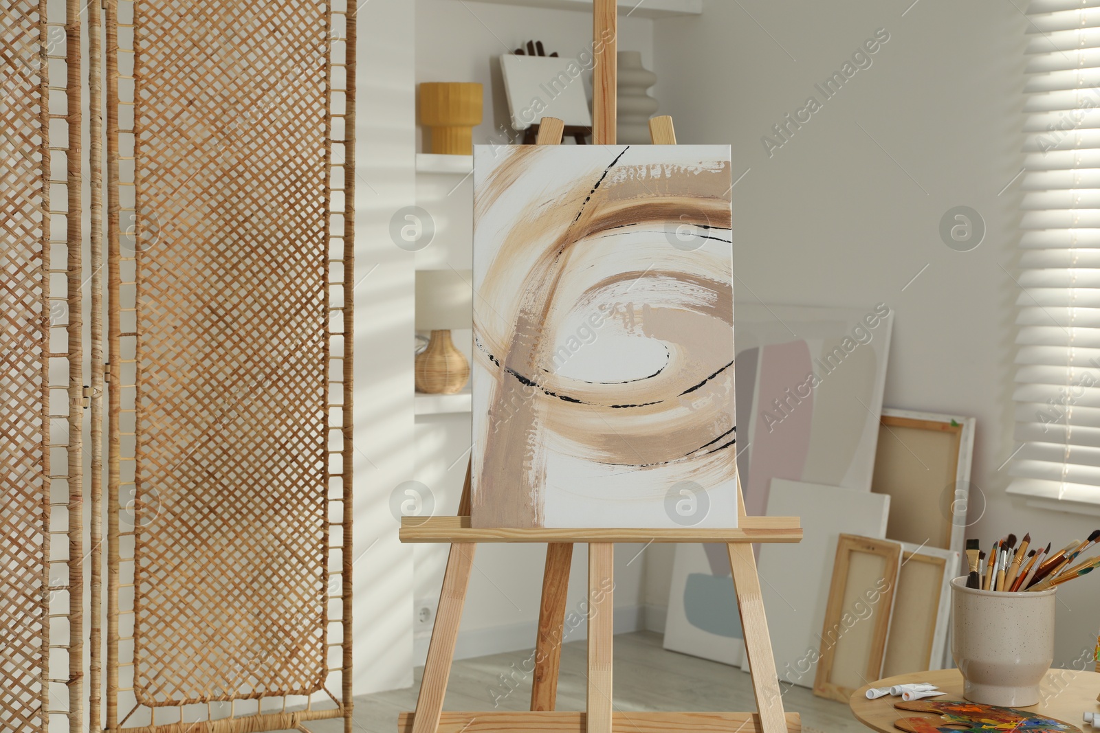 Photo of Folding screen and easel with beautiful abstract painting in room