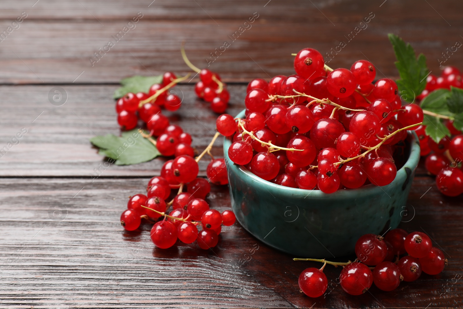 Photo of Fresh red currants and green leaves on wooden table, closeup