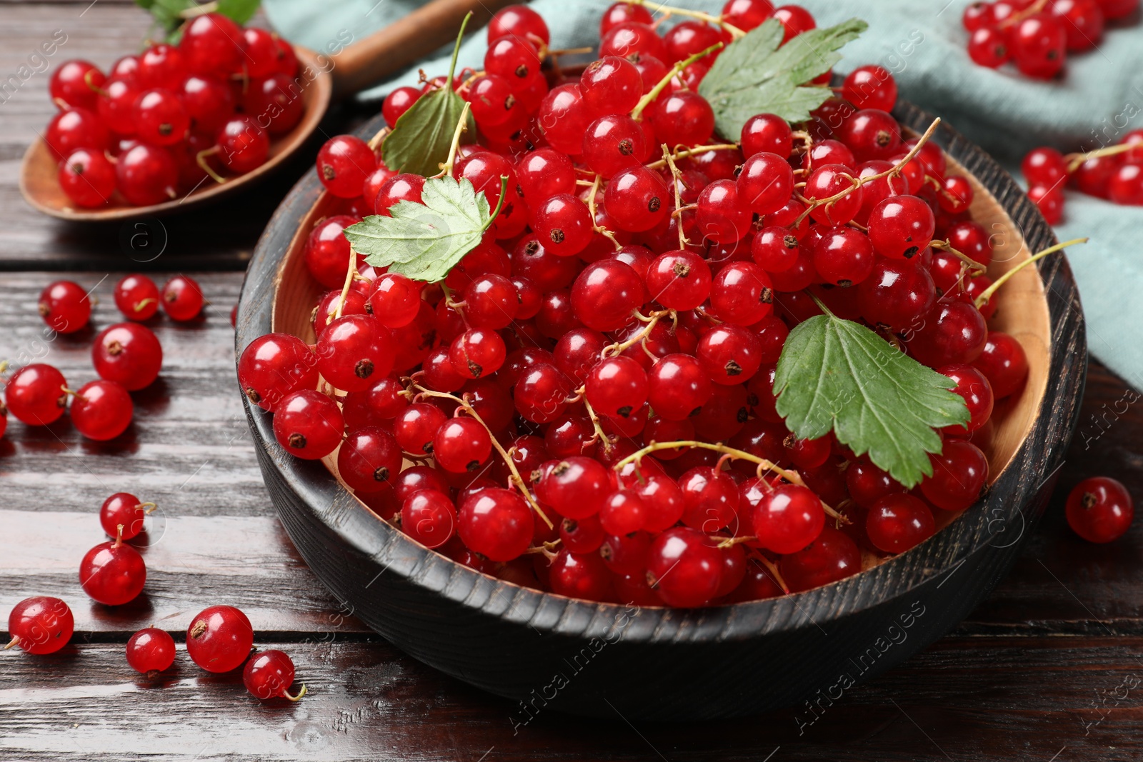 Photo of Fresh red currants and green leaves on wooden table, closeup