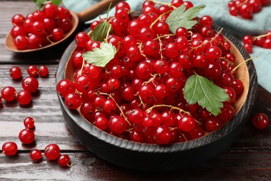 Photo of Fresh red currants and green leaves on wooden table, closeup