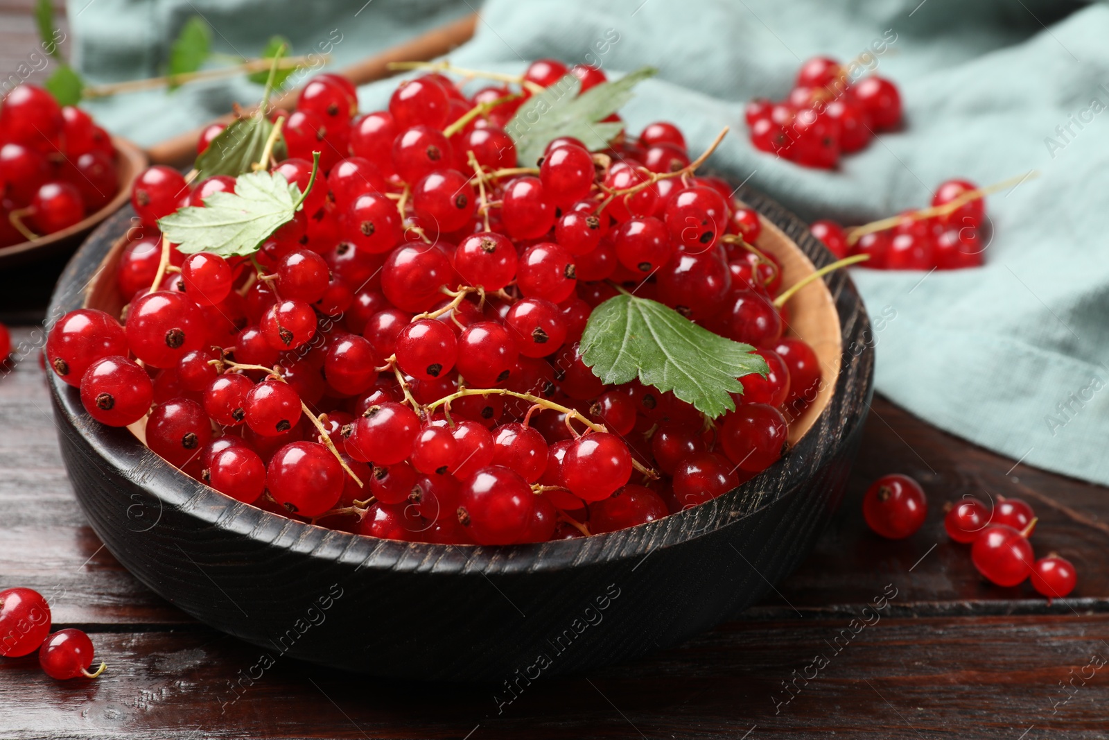 Photo of Fresh red currants and green leaves on wooden table, closeup