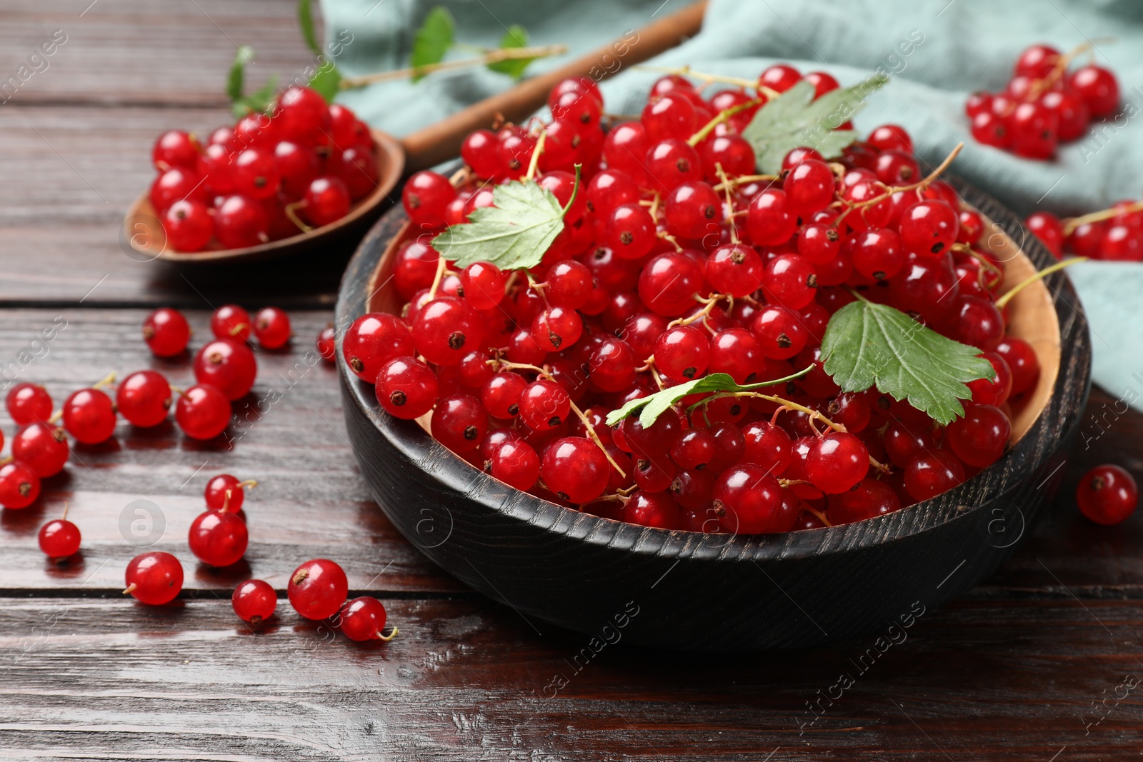 Photo of Fresh red currants and green leaves on wooden table, closeup