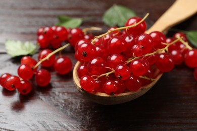 Photo of Fresh red currants in spoon on wooden table, closeup