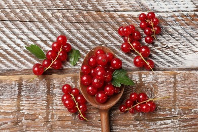 Photo of Fresh red currants and green leaves on wooden table, top view