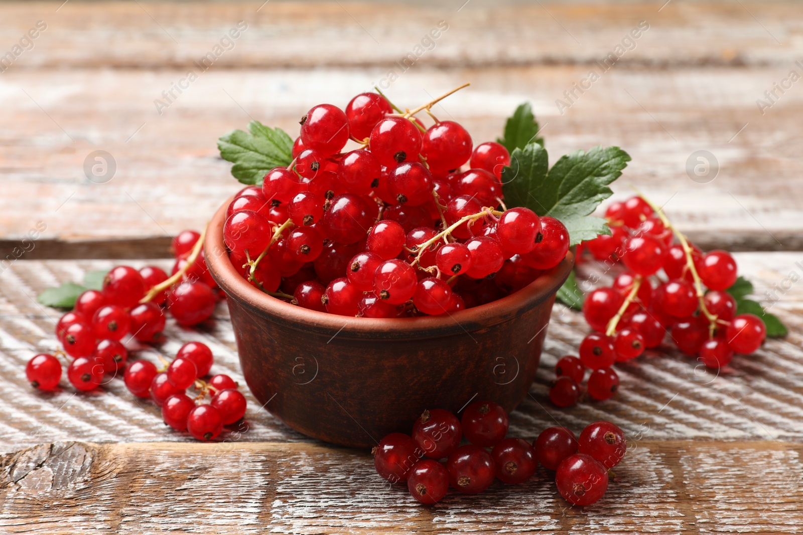 Photo of Fresh red currants in bowl on wooden table, closeup