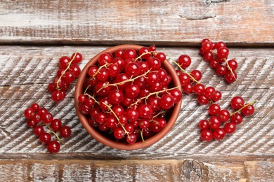 Photo of Fresh red currants in bowl on wooden table, top view