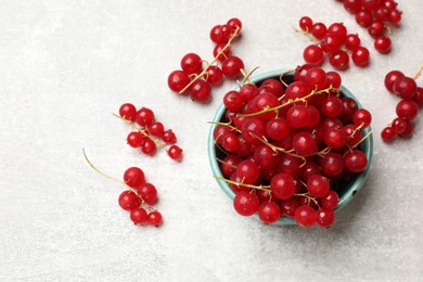 Photo of Fresh red currant in bowl on light table, top view