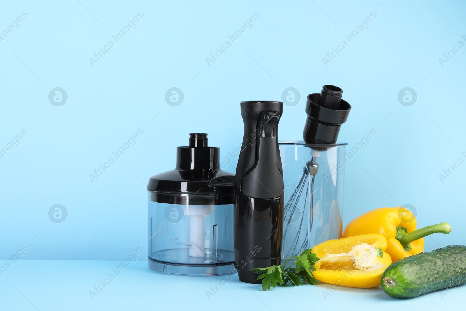 Photo of Hand blender kit and fresh vegetables on light blue background, space for text