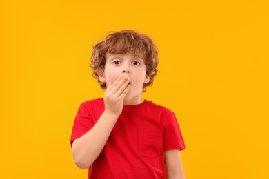 Photo of Portrait of emotional little boy on orange background