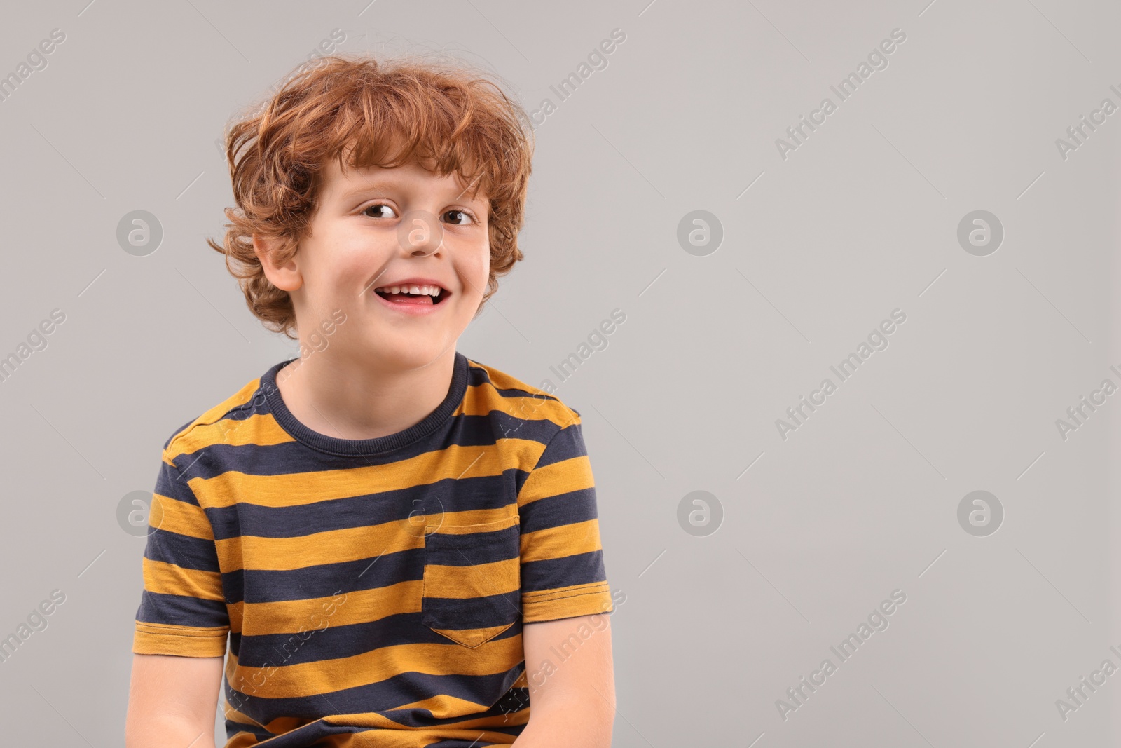 Photo of Portrait of cute little boy on grey background, space for text