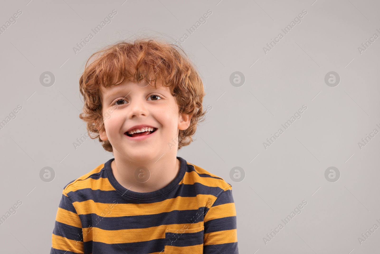 Photo of Portrait of cute little boy on grey background, space for text