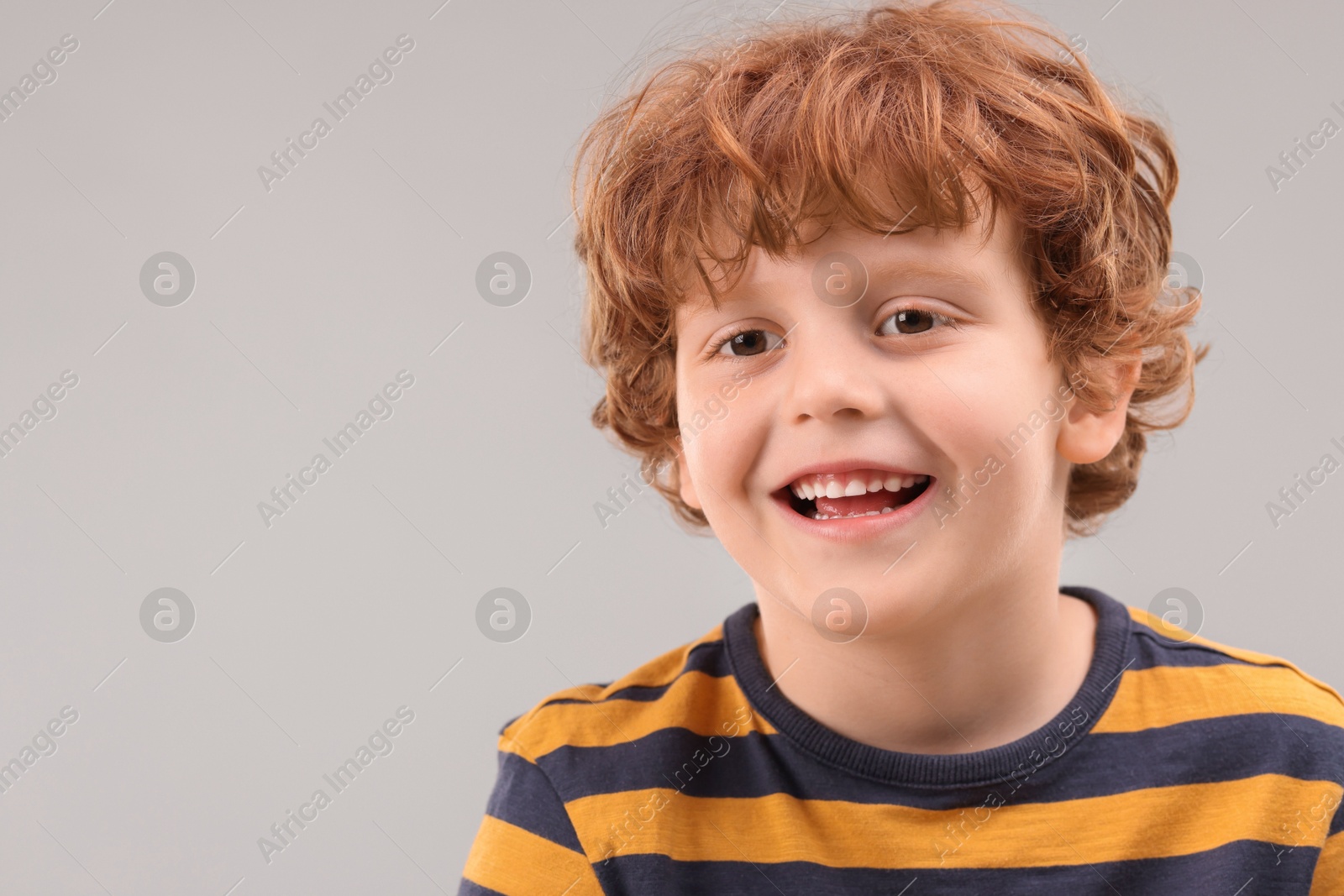 Photo of Portrait of cute little boy on grey background, space for text