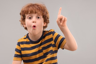 Photo of Portrait of emotional little boy pointing at something on grey background