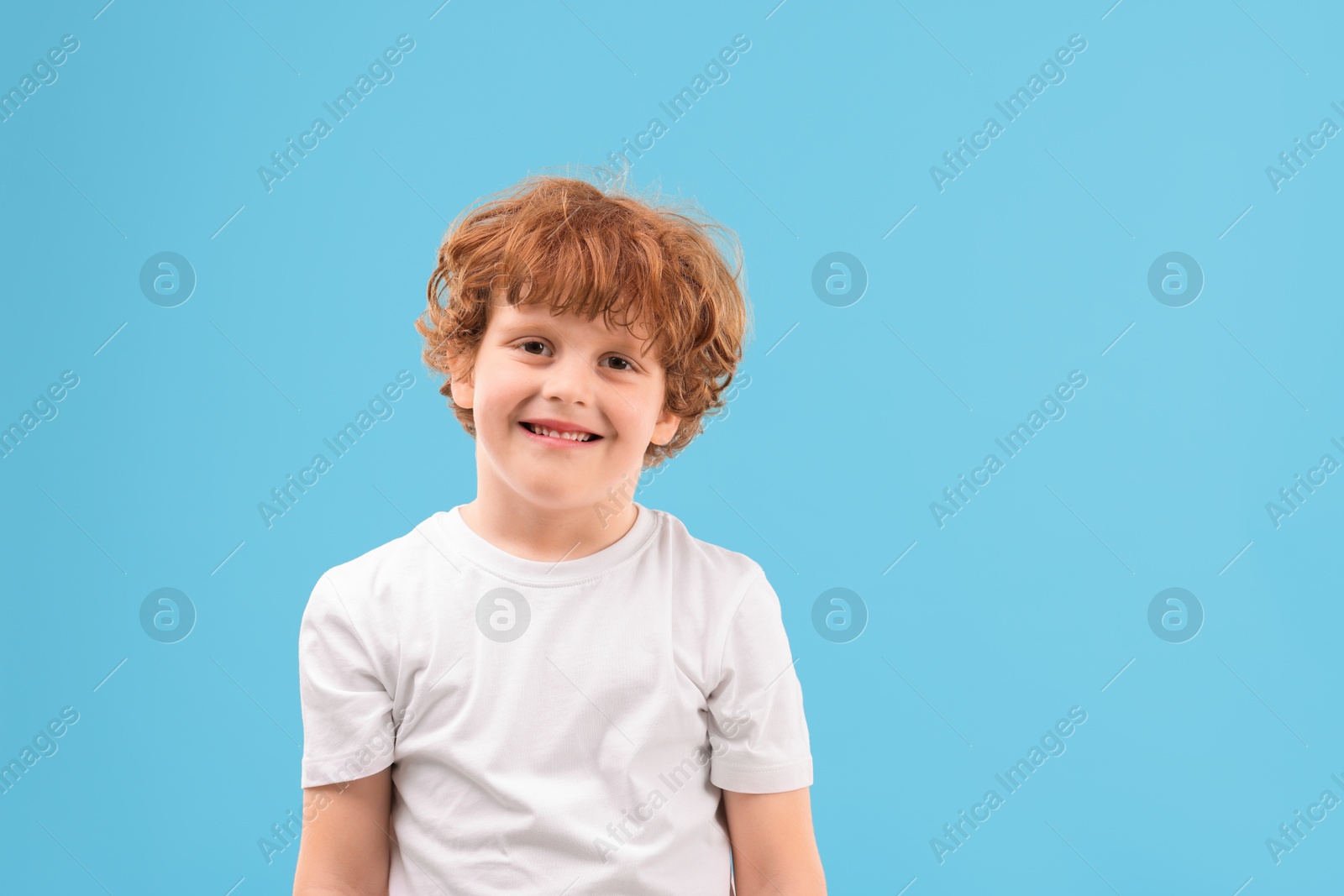 Photo of Portrait of cute little boy on light blue background. Space for text