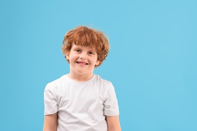 Photo of Portrait of cute little boy on light blue background. Space for text