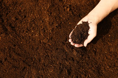 Woman holding pile of soil outdoors, top view. Space for text