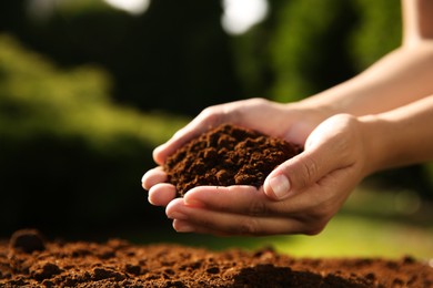 Woman holding pile of soil outdoors, closeup. Space for text