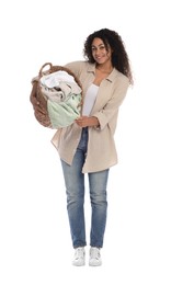 Happy woman with basket full of laundry on white background