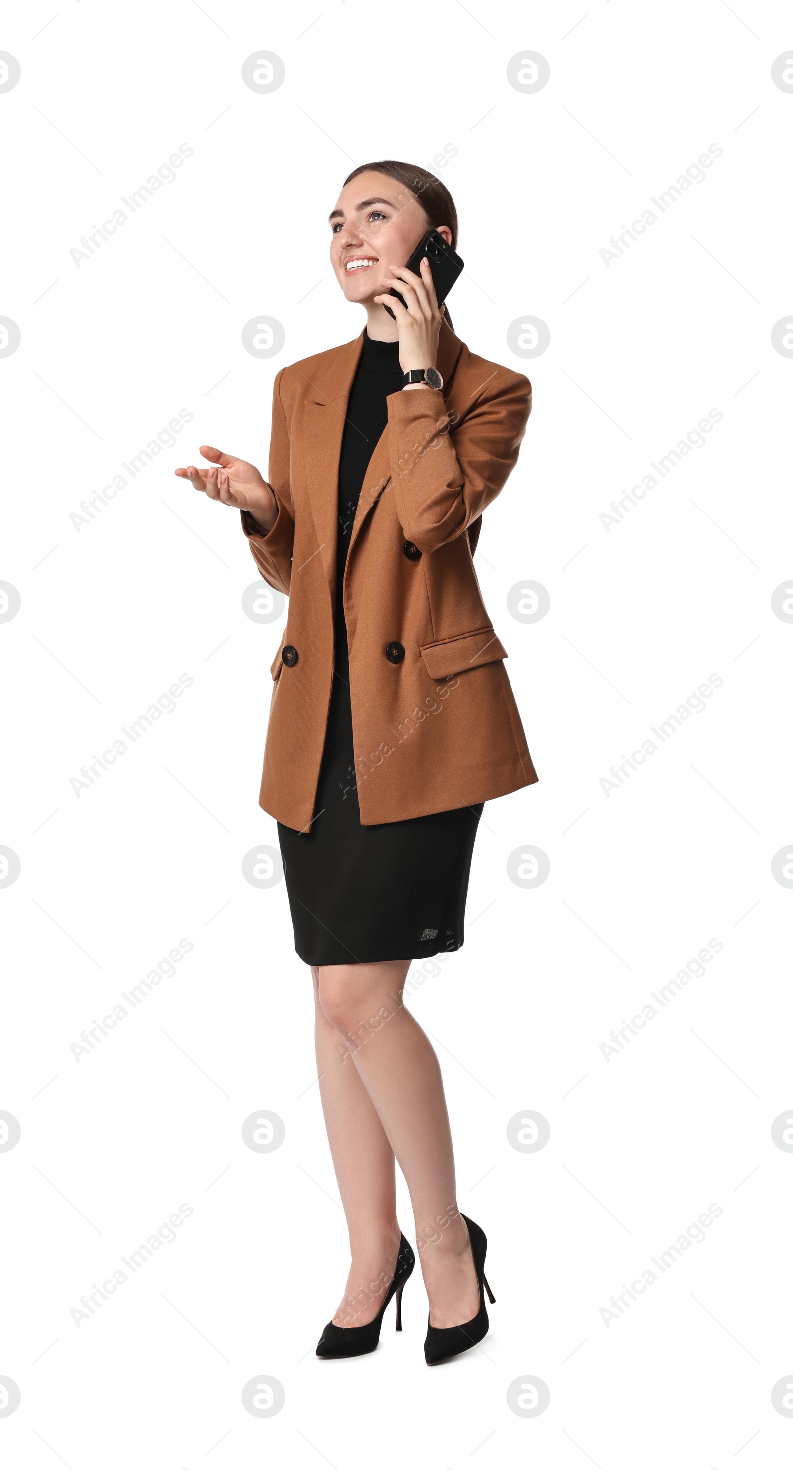 Photo of Beautiful woman in brown jacket and black dress talking on smartphone against white background