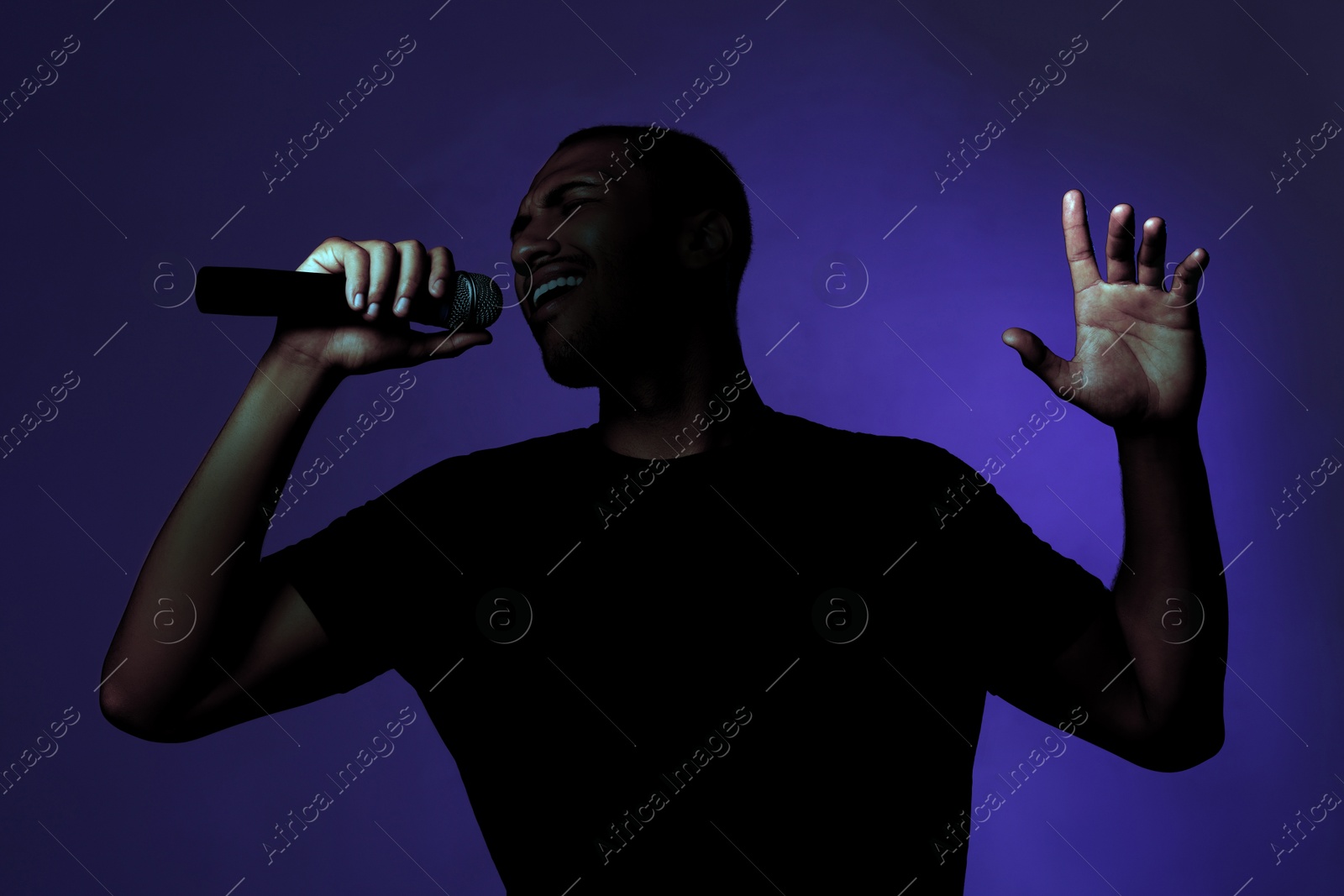 Image of Singer performing on stage. Young man with microphone