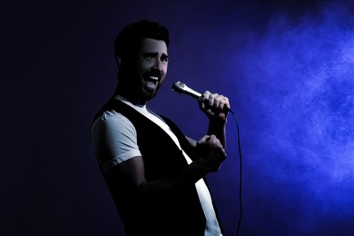 Image of Singer performing on stage. Man with microphone in smoke