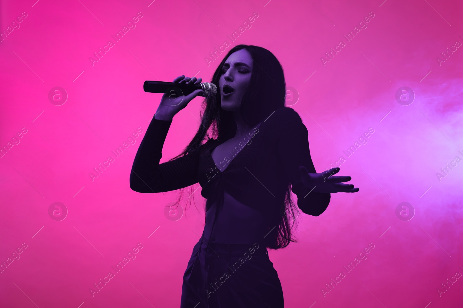 Image of Singer performing on stage. Young woman with microphone