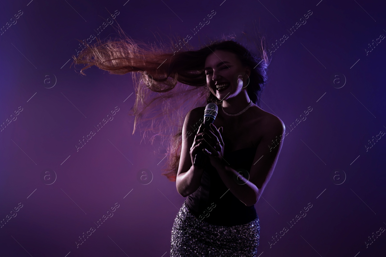 Image of Singer performing on stage. Young woman with microphone
