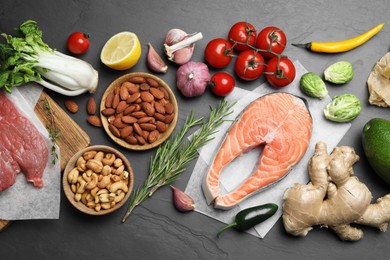 Photo of Flat lay composition with fresh fish and other products for balanced diet on black table