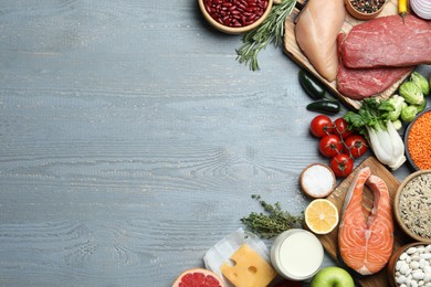 Flat lay composition with fresh meat and other products on grey wooden table, space for text. Balanced diet