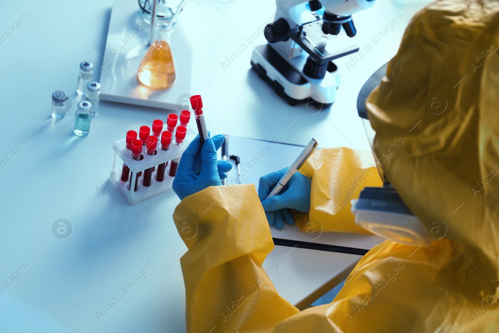 Photo of Scientist in chemical protective suit working with blood samples at laboratory, closeup. Virus research