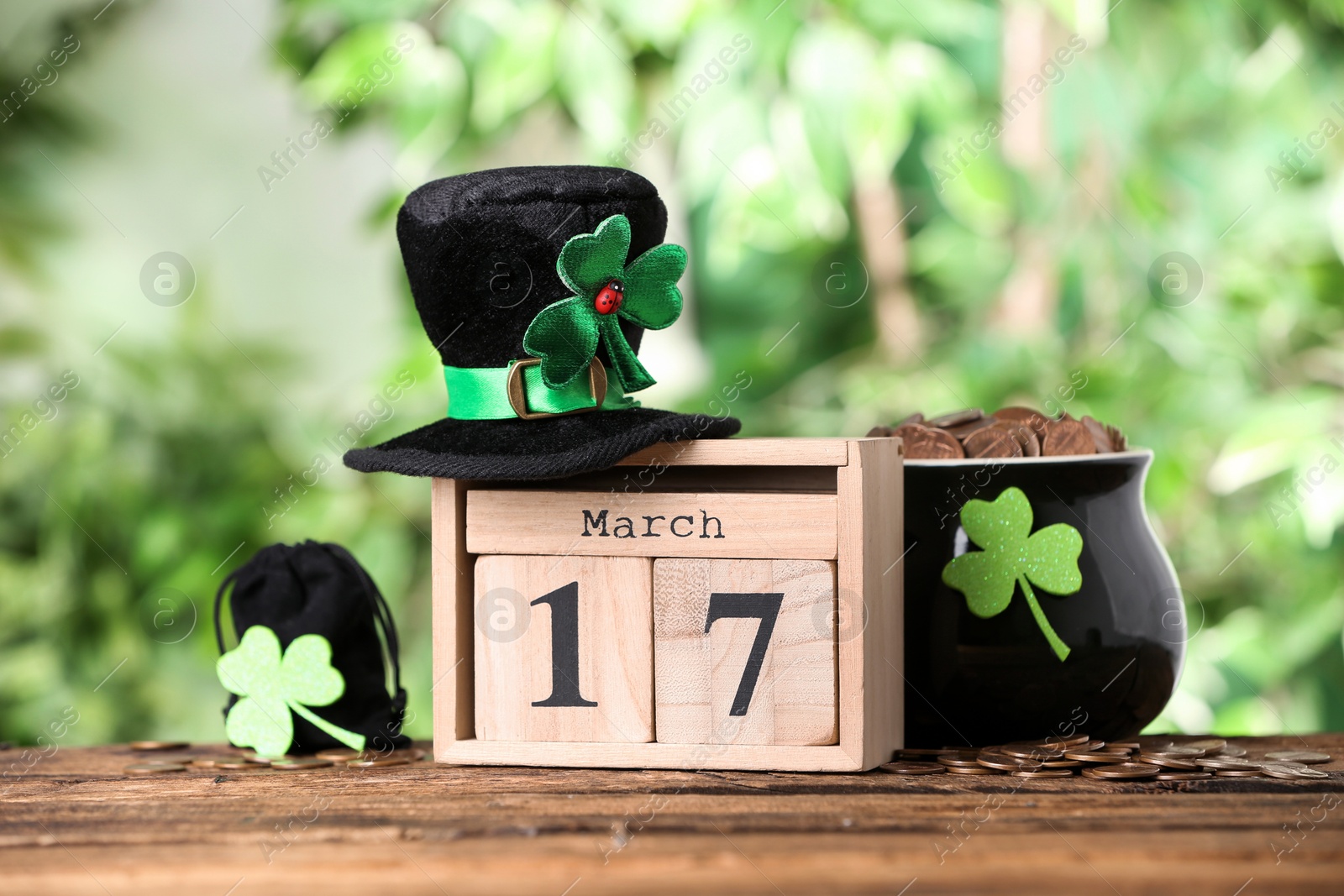 Photo of Composition with block calendar on wooden table against blurred greenery. St. Patrick's Day celebration