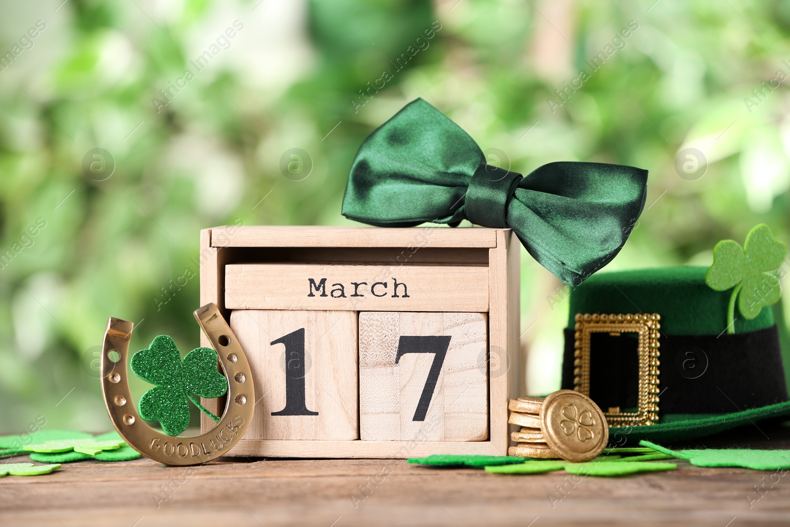 Photo of Composition with block calendar on wooden table against blurred greenery. St. Patrick's Day celebration